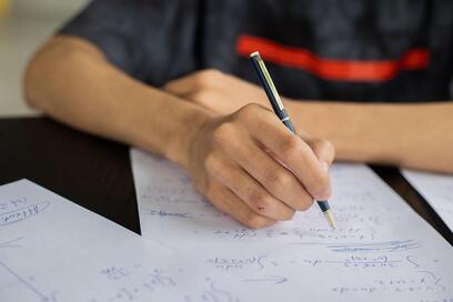 College student holding a pen working on his calculus homework.