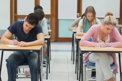 Students taking a test while sitting at desks arranged in rows.
